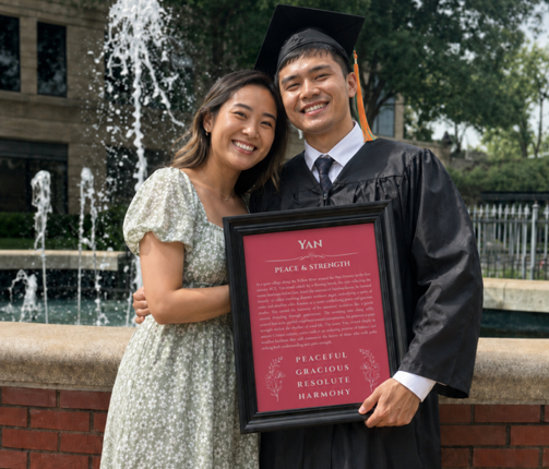 Graduate holding a personalized name meaning print with a loved one after graduation