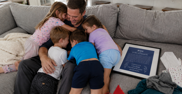 Father hugging his children beside a personalized name meaning print on Father's Day