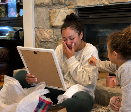 Mother opening a personalized name meaning print as a Mother's Day gift while becoming emotional